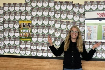 SpartanNash Associate Engagement Coordinator, Jessica Trexler, showcasing a wall of Junior Achievement donation cards from store guests.